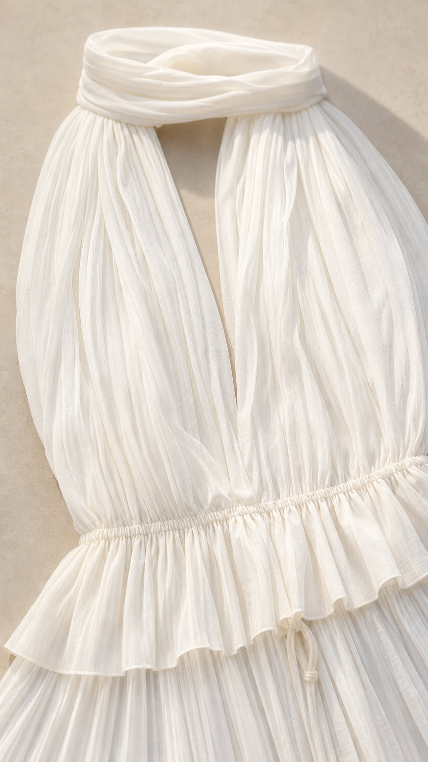 Close-up detail of white pleated fabric and halter neckline