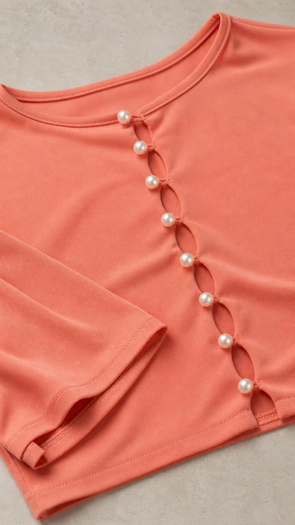 Close-up detail of faux-pearl buttons on peach crop top