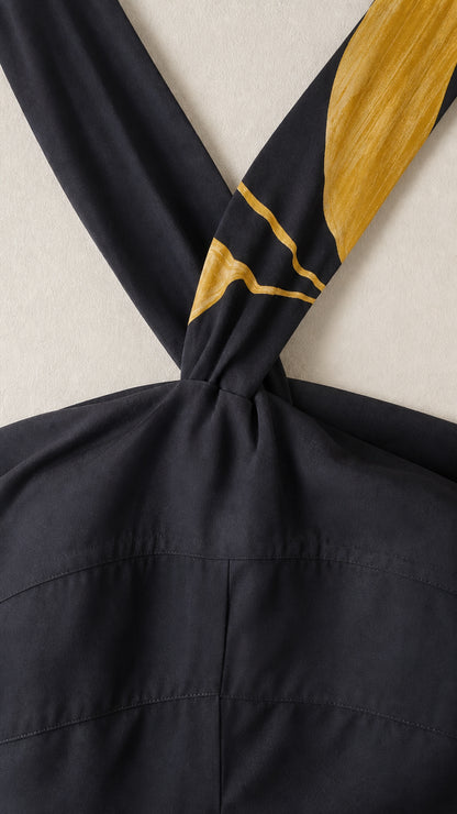 Close-up detail of the halter neckline and golden leaf strap accent