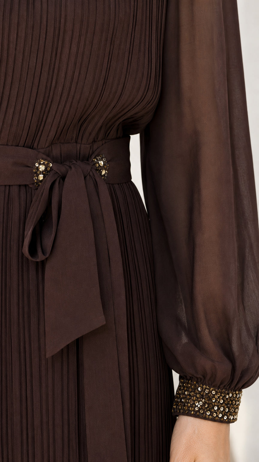 Close-up of beaded cuff, pleated bodice, and waist tie on dark brown dress