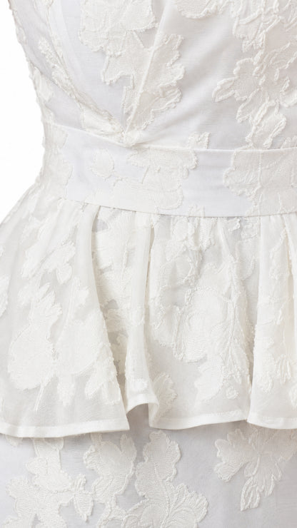 Close-up detail of white floral jacquard fabric and peplum waist seam