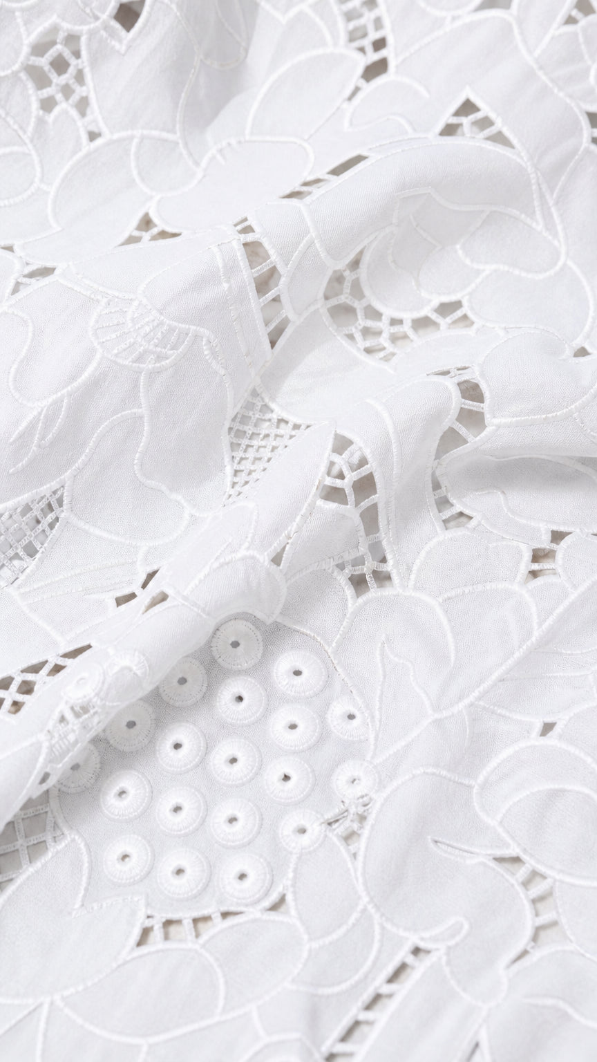 Close-up detail of white embroidered eyelet lace fabric