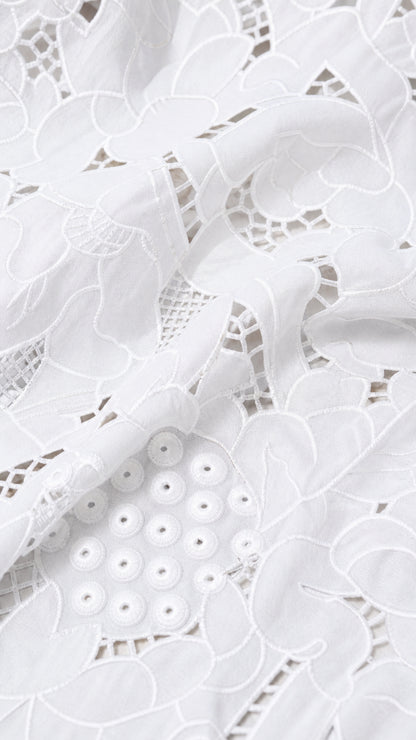 Close-up detail of white embroidered eyelet lace fabric