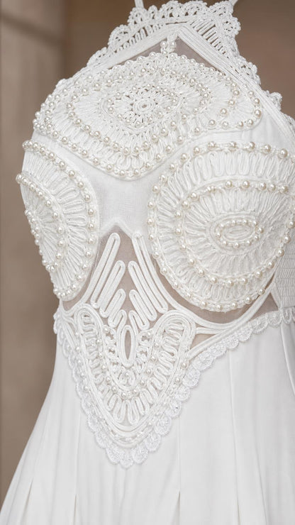 Close-up detail of ornate beaded and embroidered bodice on white dress