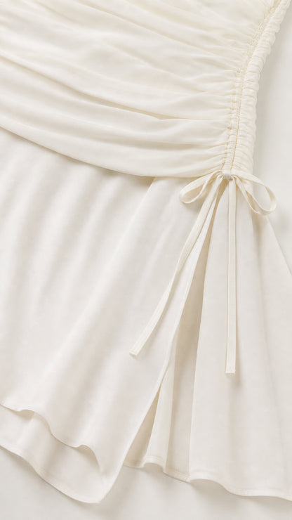 Close-up of fabric texture and drawstring side detail on white dress
