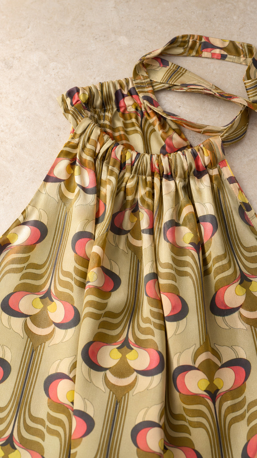 Close-up detail of gathered halter neckline and geometric fabric pattern