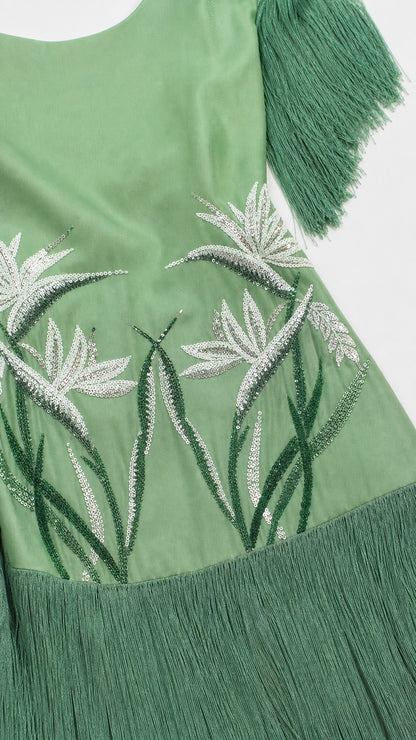 Close-up detail of white botanical embroidery on sage green fabric