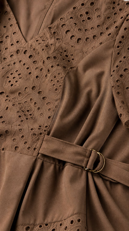 Close-up detail of mocha brown eyelet embroidery and side belt buckle