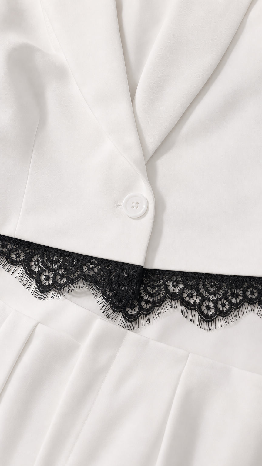 Close-up detail of blazer button and black lace trim on white fabric