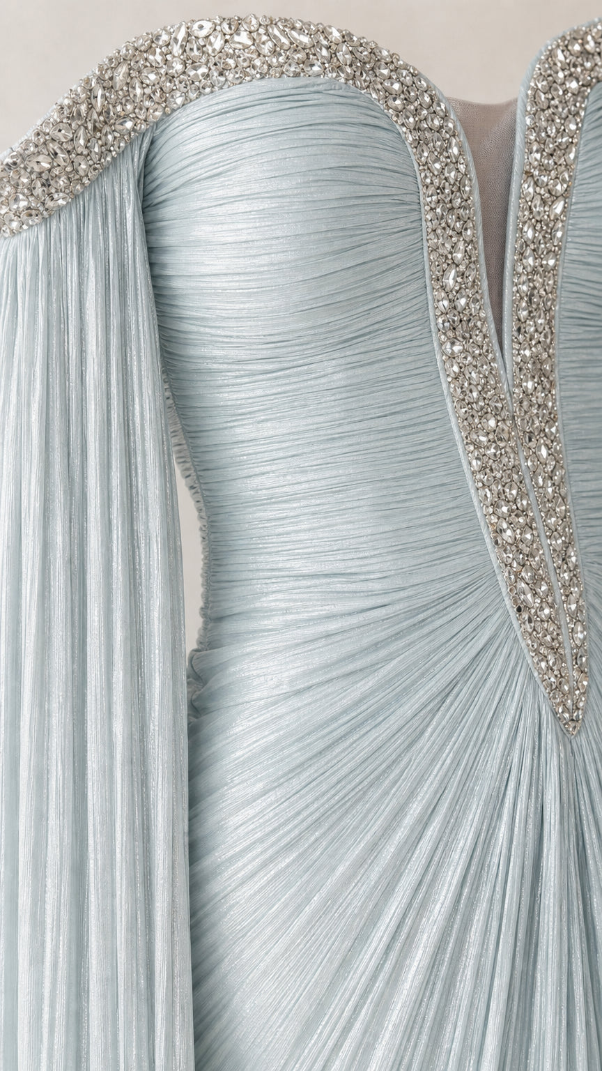 Close-up detail of crystal-beaded off-the-shoulder neckline and pleated bodice on ice blue gown