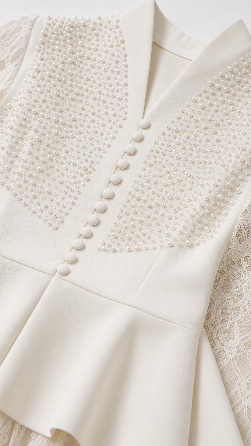 Close-up of pearl beadwork and fabric buttons on white bodice