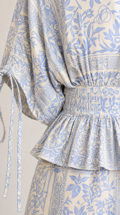 Close-up detail of smocked peplum waist and sleeve tie