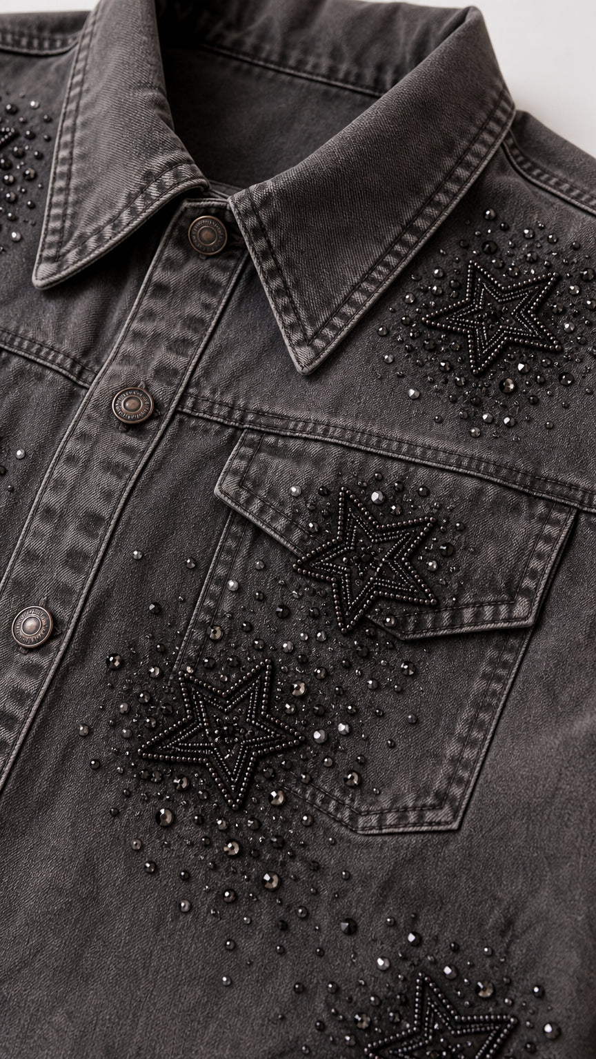 Close-up detail of rhinestone and beaded star embellishments on washed grey denim jacket pocket