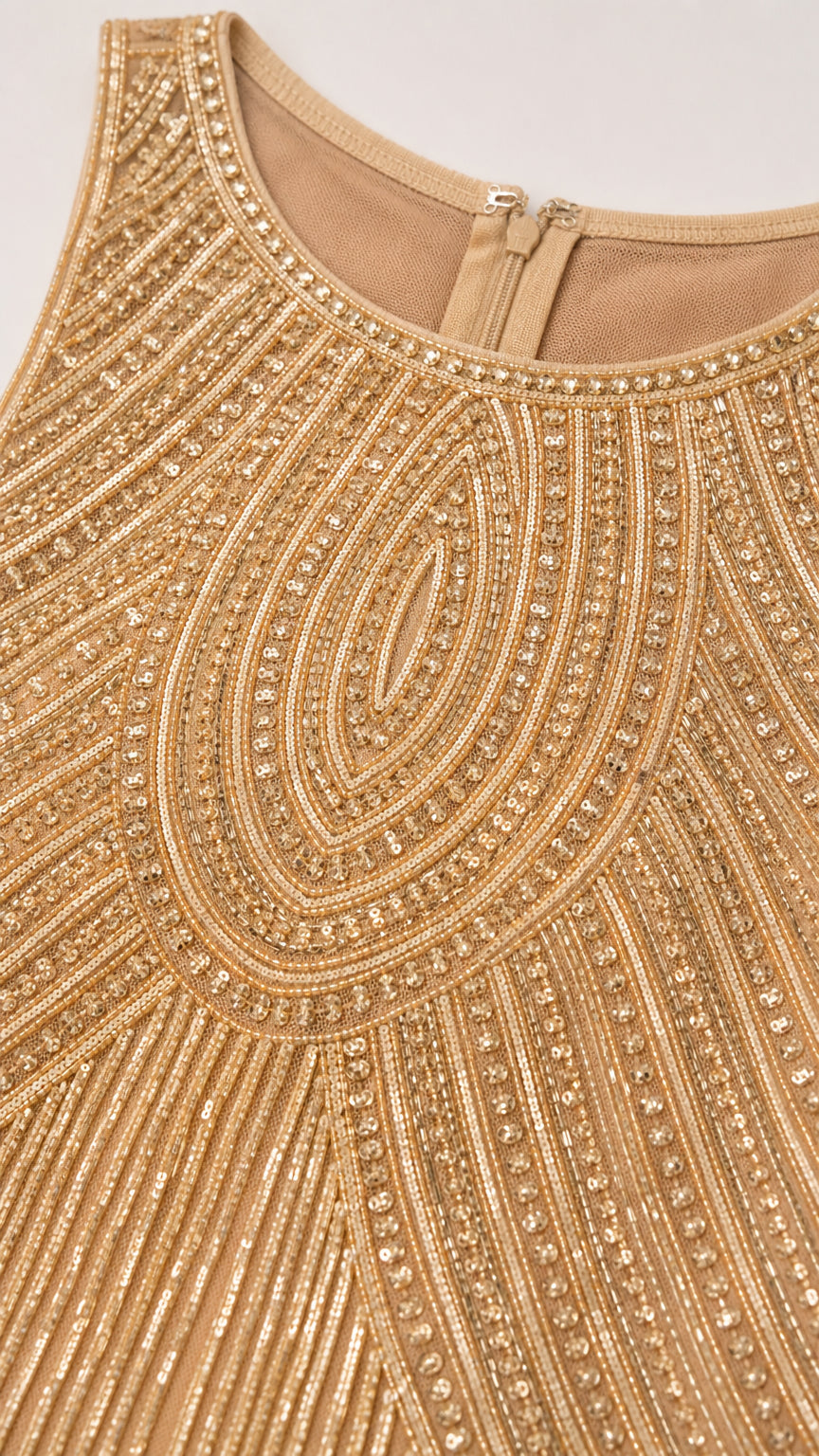 Close up of neckline and intricate gold bead and sequin pattern on mesh fabric