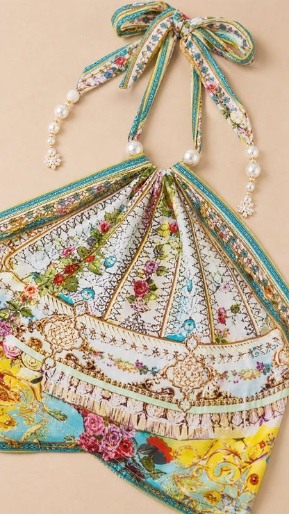 Close-up detail of pearl-beaded halter straps and floral printed fabric