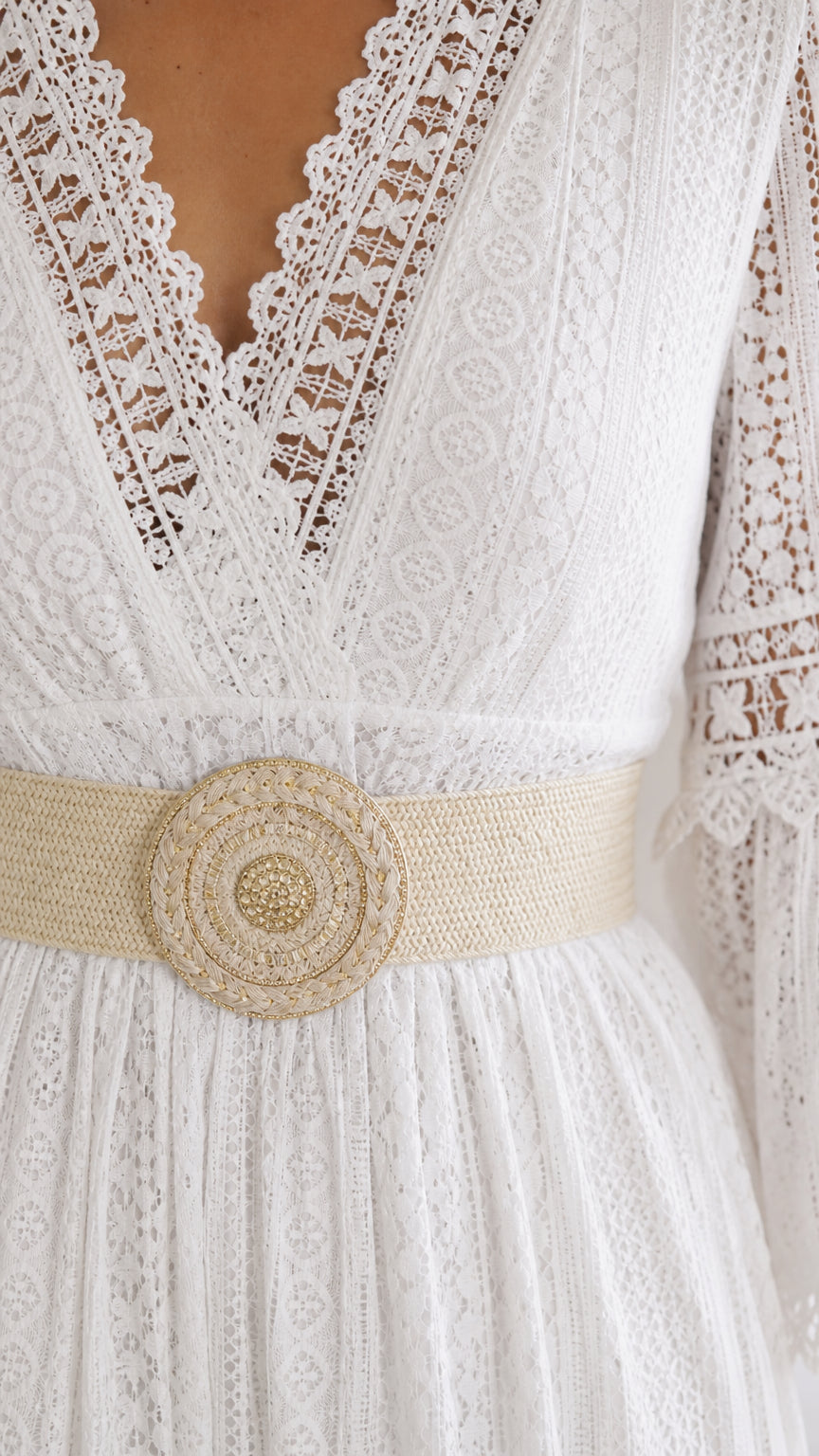 Close-up detail of V-neckline and woven belt on white lace dress