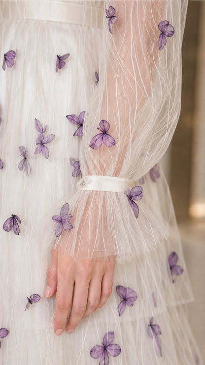 Close-up detail of sheer sleeve cuff with purple 3D butterfly appliques and ruffles