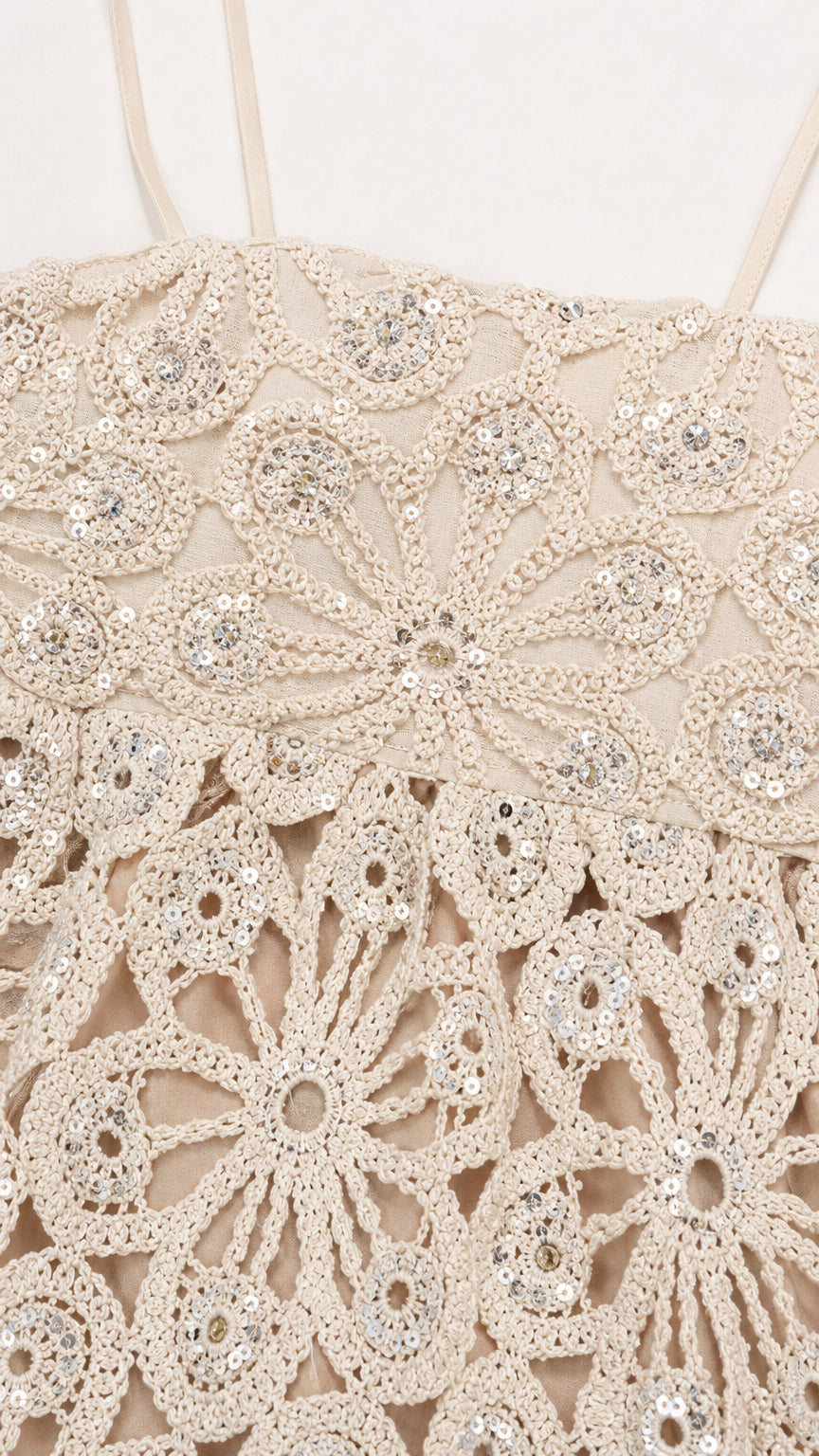 Close-up detail of floral crochet pattern and sequins on ivory top