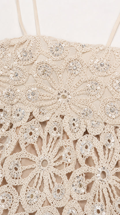 Close-up detail of floral crochet pattern and sequins on ivory top