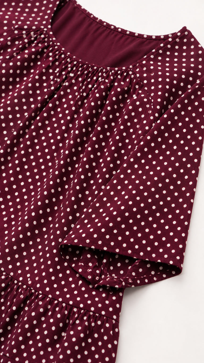 Close-up detail of burgundy polka dot gathered neckline and short sleeve