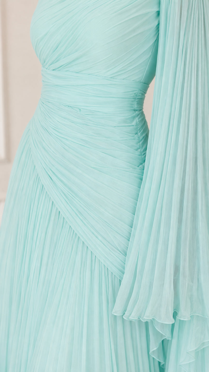 Close-up detail of aqua blue pleated bodice and draped sleeve texture