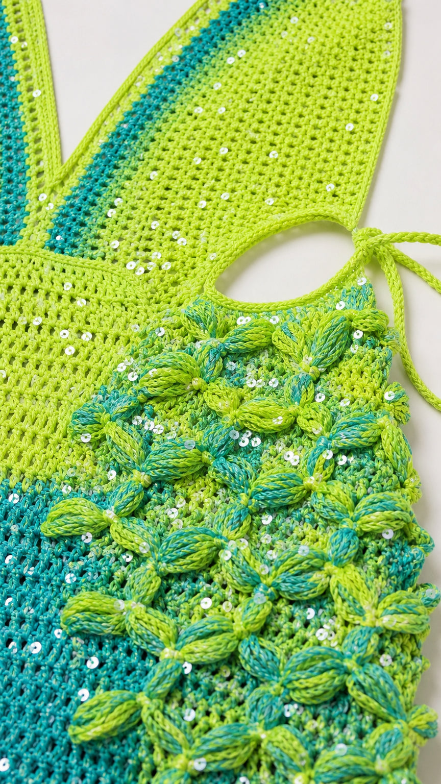 Close-up detail of green and blue crochet texture and sequin embellishments