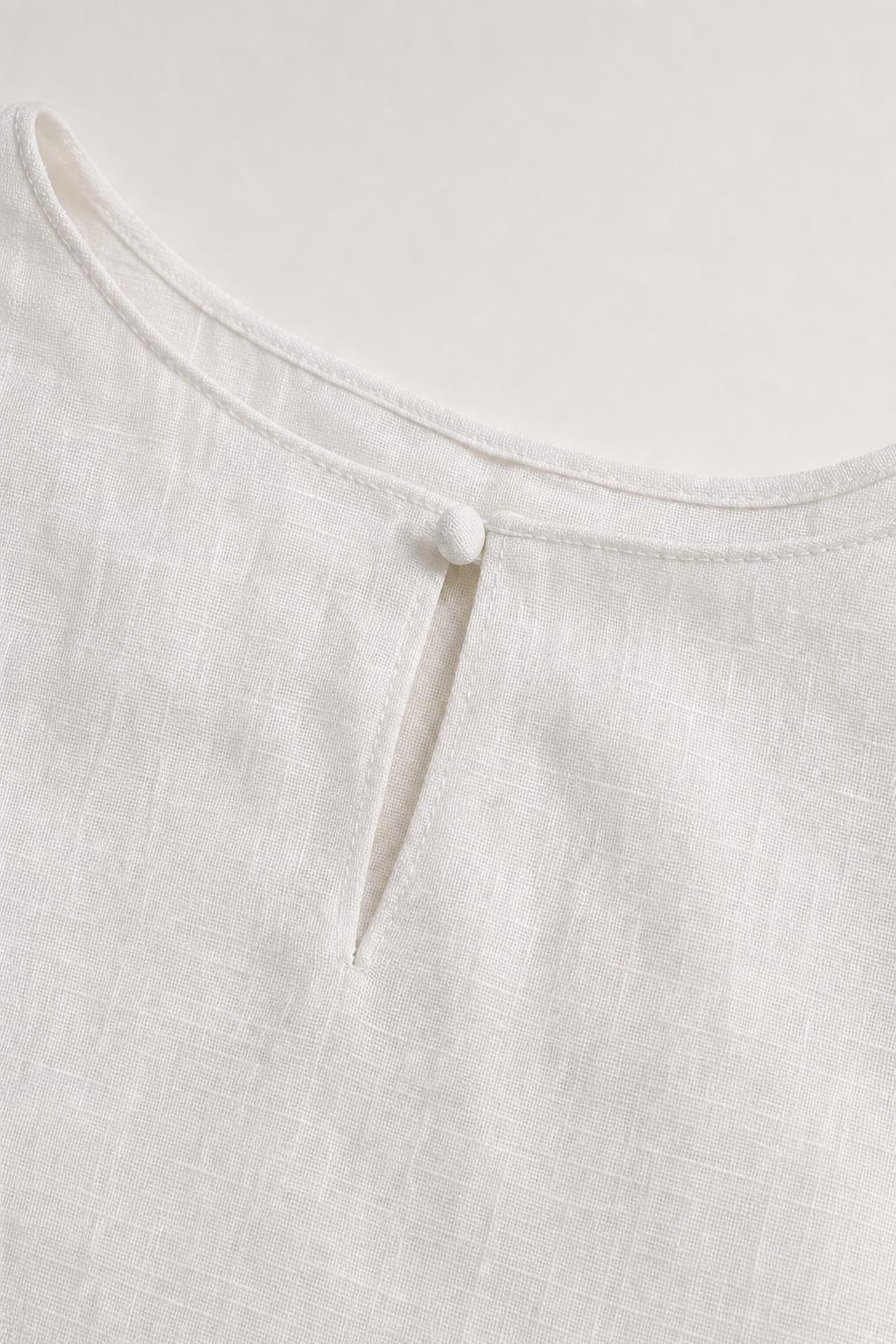 Close-up detail of white dress neckline with button closure