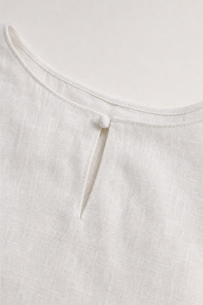 Close-up detail of white dress neckline with button closure