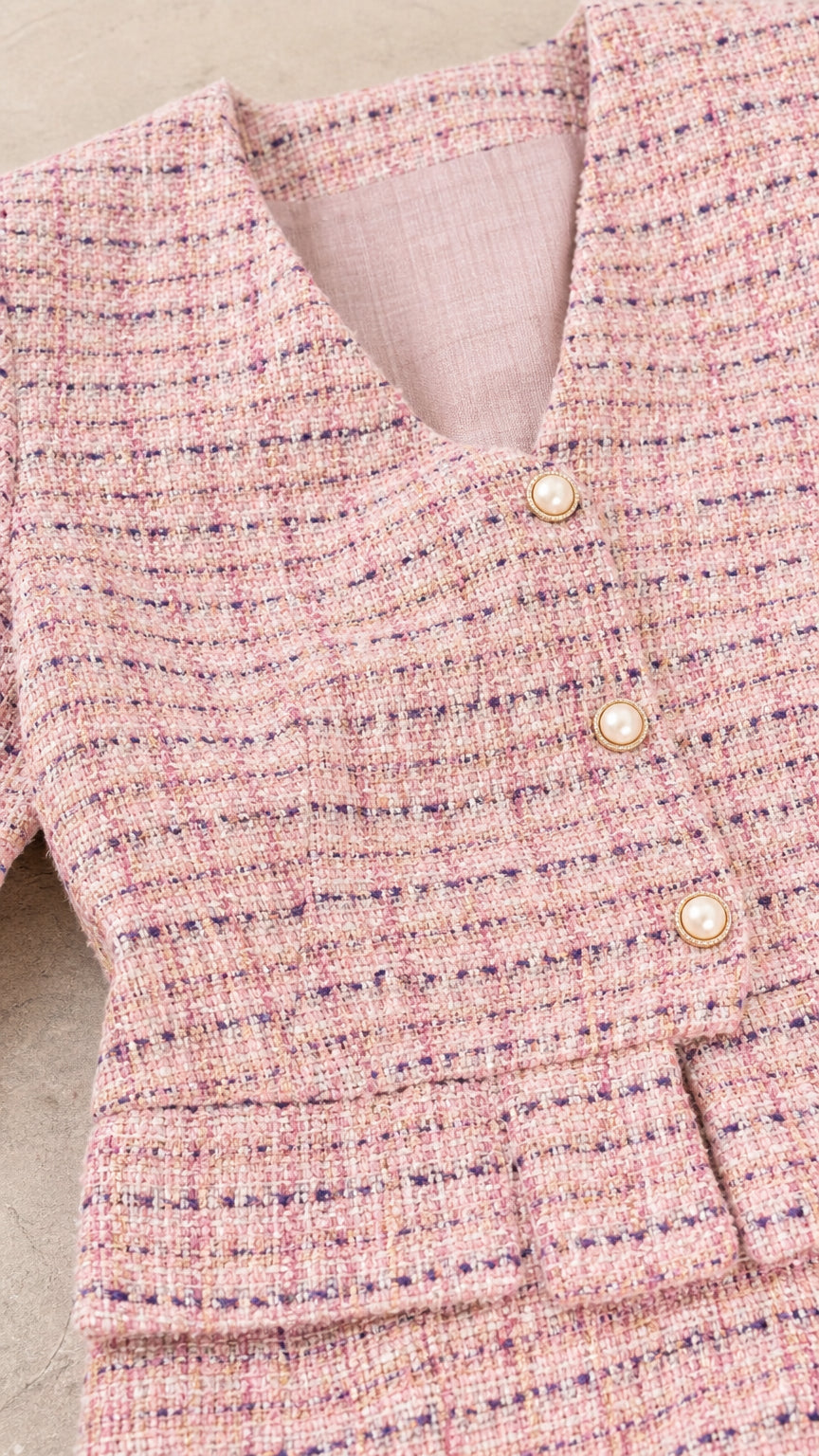 Close-up of the pink tweed-inspired texture, V-neckline, pearl-look buttons, and waistband