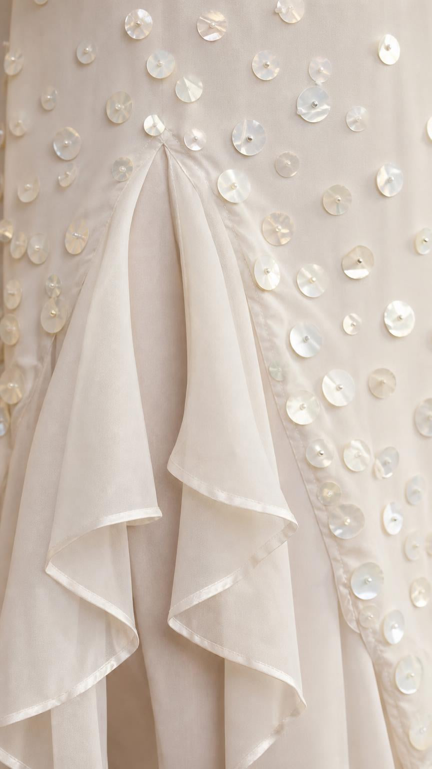 Close-up detail of white sequins and ruffled hem