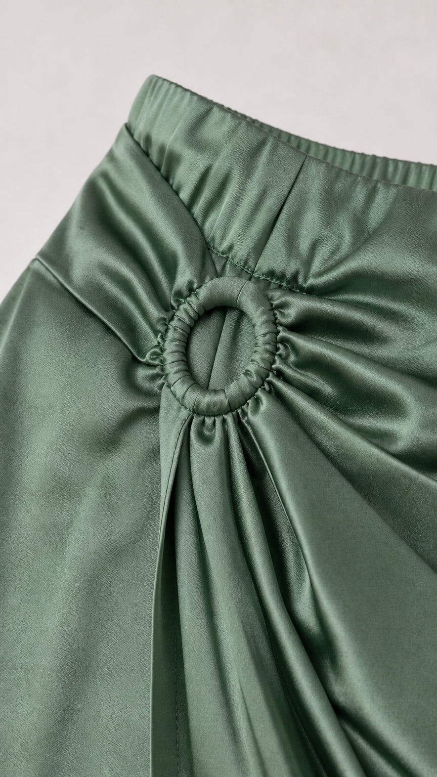 Close-up detail of the gathered ring buckle and waist ruching on the satin skirt