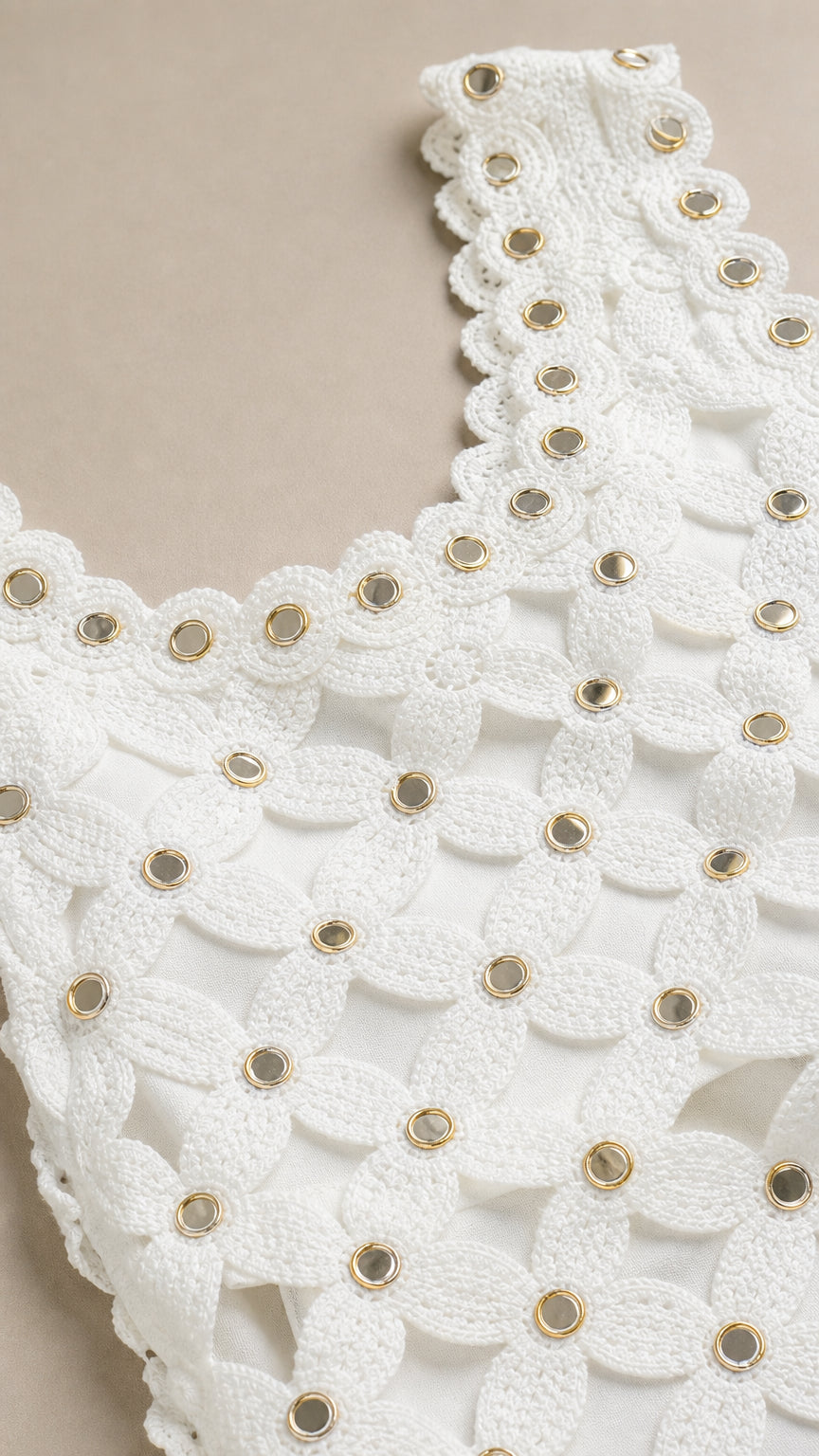 Close-up detail of white crochet neckline with metallic grommets