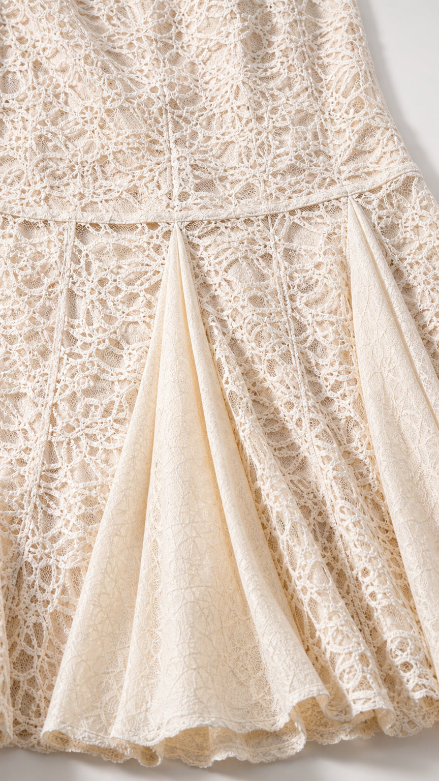 Close-up detail of textured floral lace and pleated godet hem design