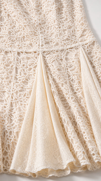 Close-up detail of textured floral lace and pleated godet hem design