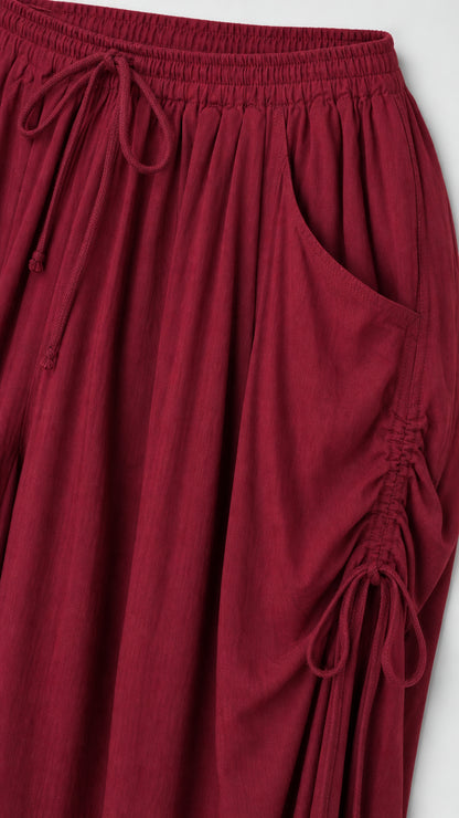 Close-up detail of side pocket and drawstring on burgundy pants
