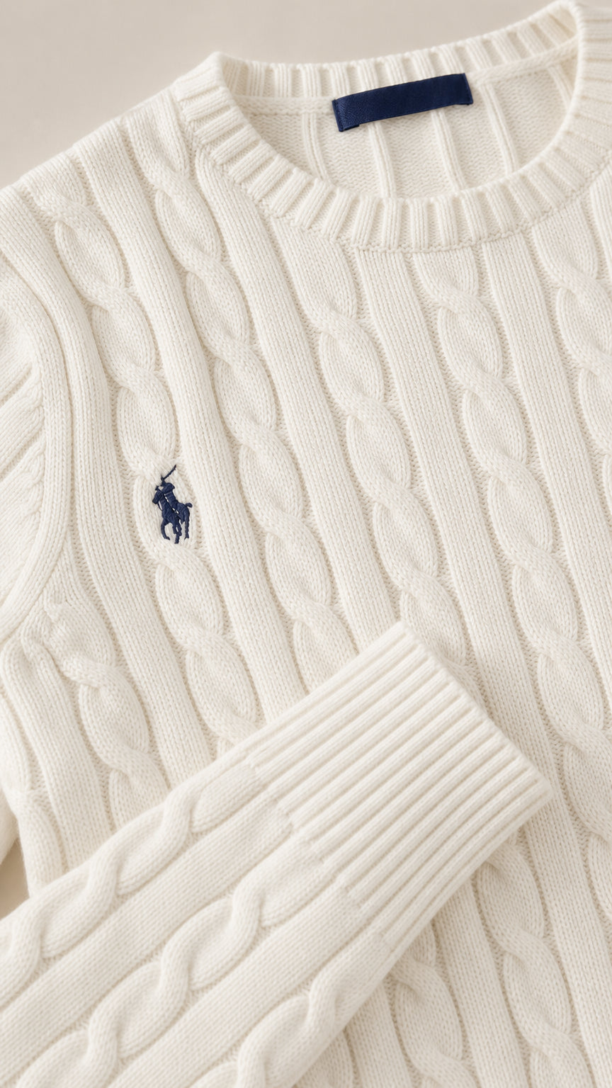 Close up of white cable-knit pattern fabric, crew neckline, and ribbed cuff detail