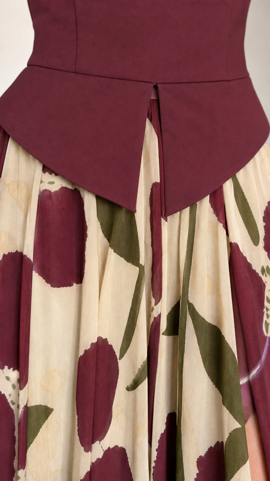 Close-up detail of structured burgundy bodice and gathered floral skirt