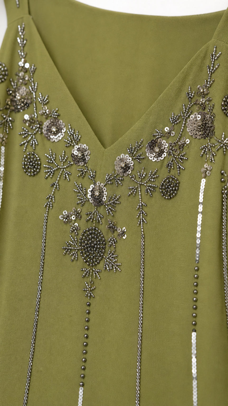 Close-up detail of silver sequin and bead embroidery along the V-neckline on olive green fabric