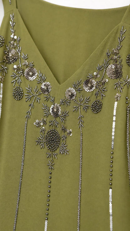 Close-up detail of silver sequin and bead embroidery along the V-neckline on olive green fabric