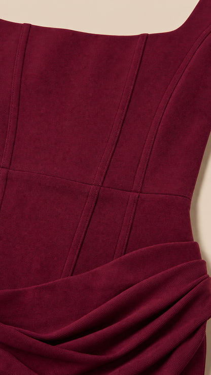Close-up of bodice seams and draped hip detail on burgundy dress