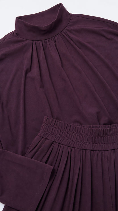 Close-up detail of gathered mock neckline and elasticated pleated waistband in plum
