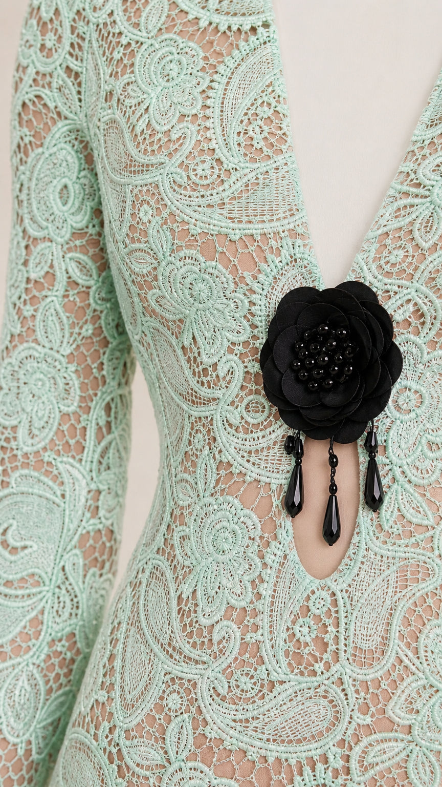 Close-up of plunging V-neckline and black floral brooch detail on lace dress