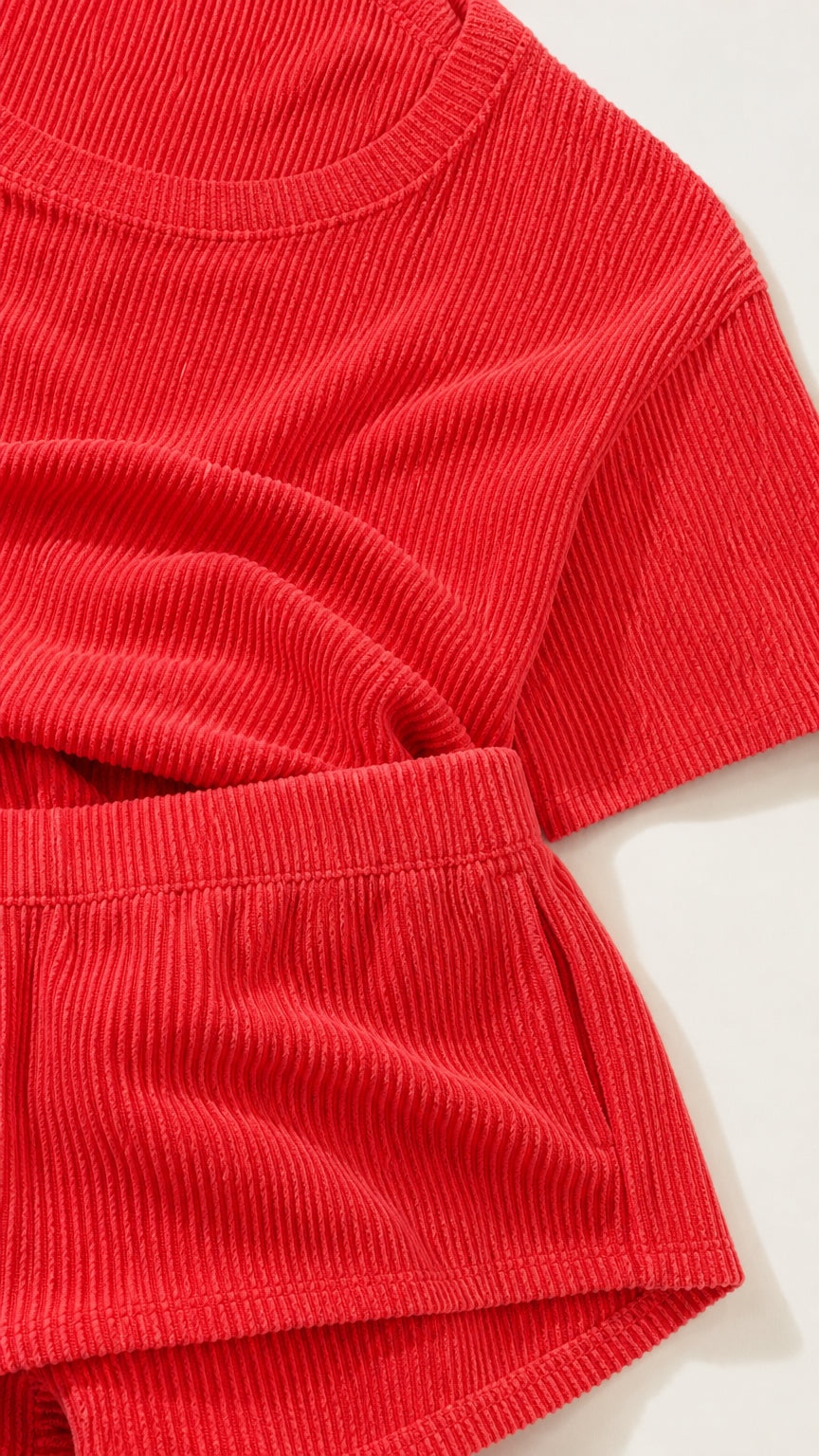 Close-up detail of textured red ribbed knit fabric and crew neckline