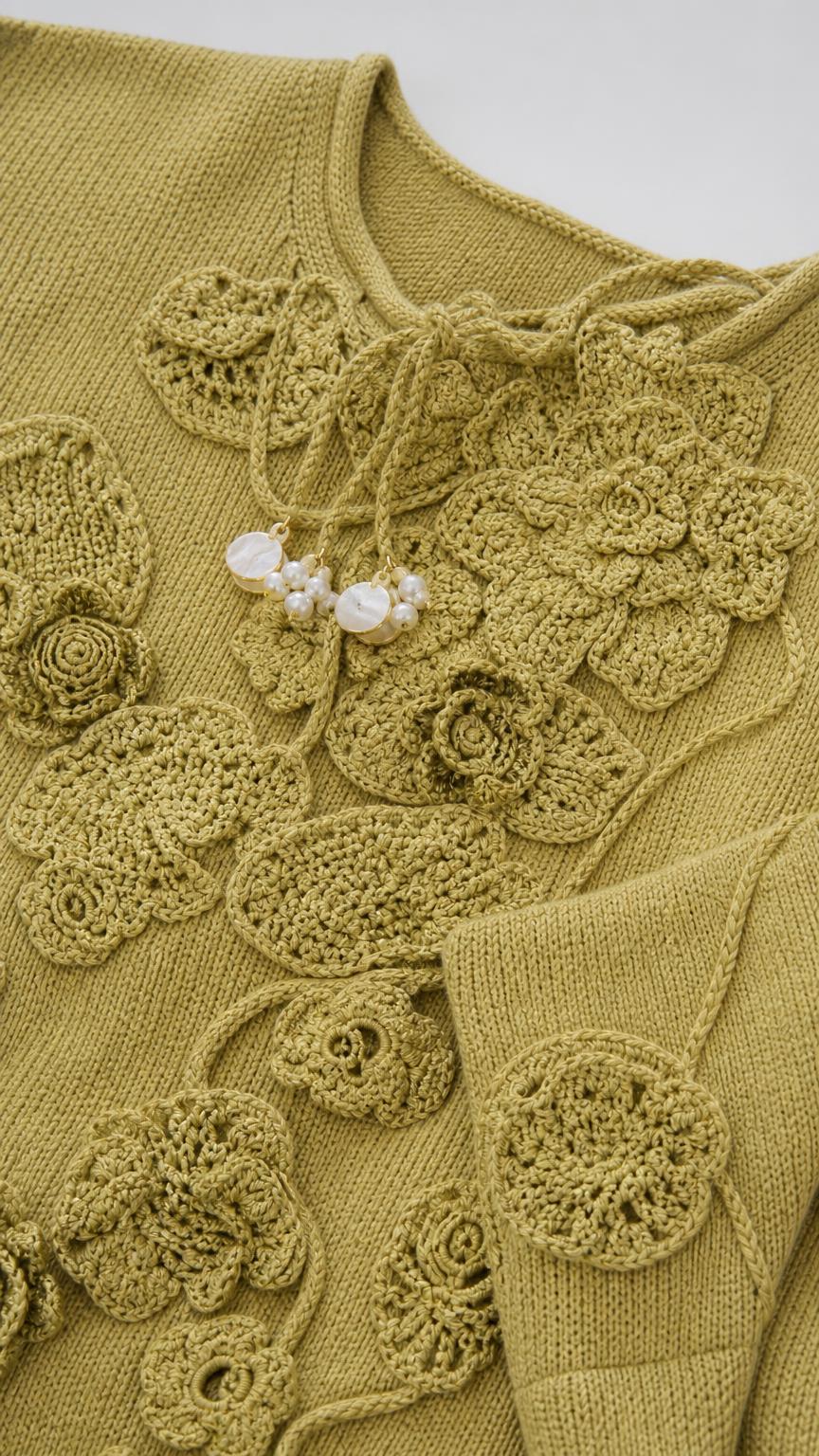Close-up detail of crochet floral appliques and pearl charms