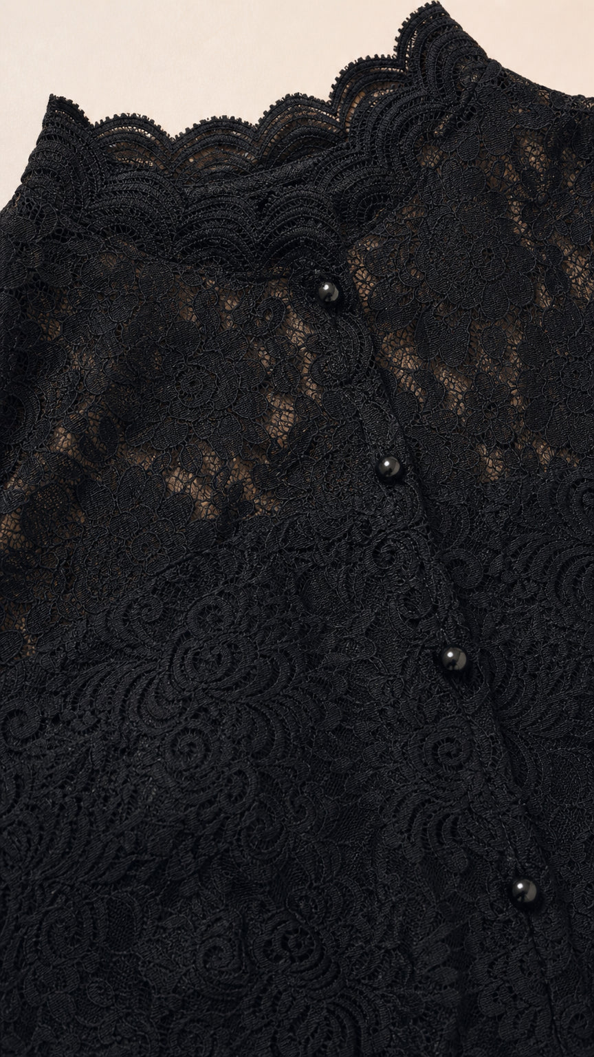 Close-up detail of delicate black floral lace, buttons, and scalloped collar