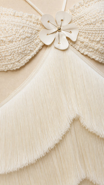 Close-up detail of textured bodice with floral applique and tiered fringe layers