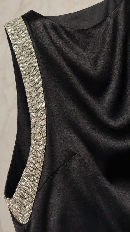 Close-up detail of rhinestone embellished side trim on black satin dress