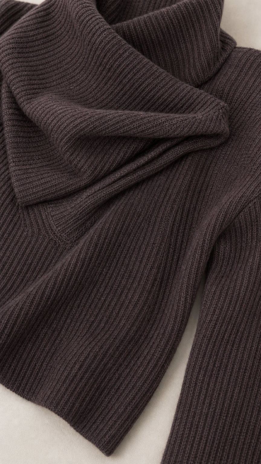 Close-up detail of dark brown ribbed knit fabric texture and asymmetrical neckline