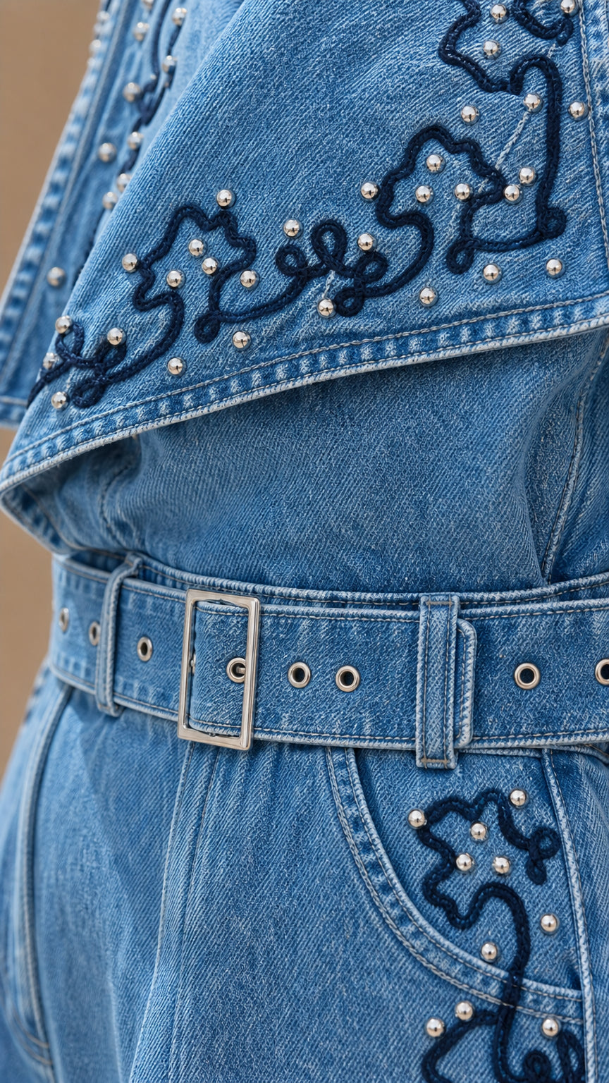 Close-up of beaded embroidery and belt detail on denim jumpsuit