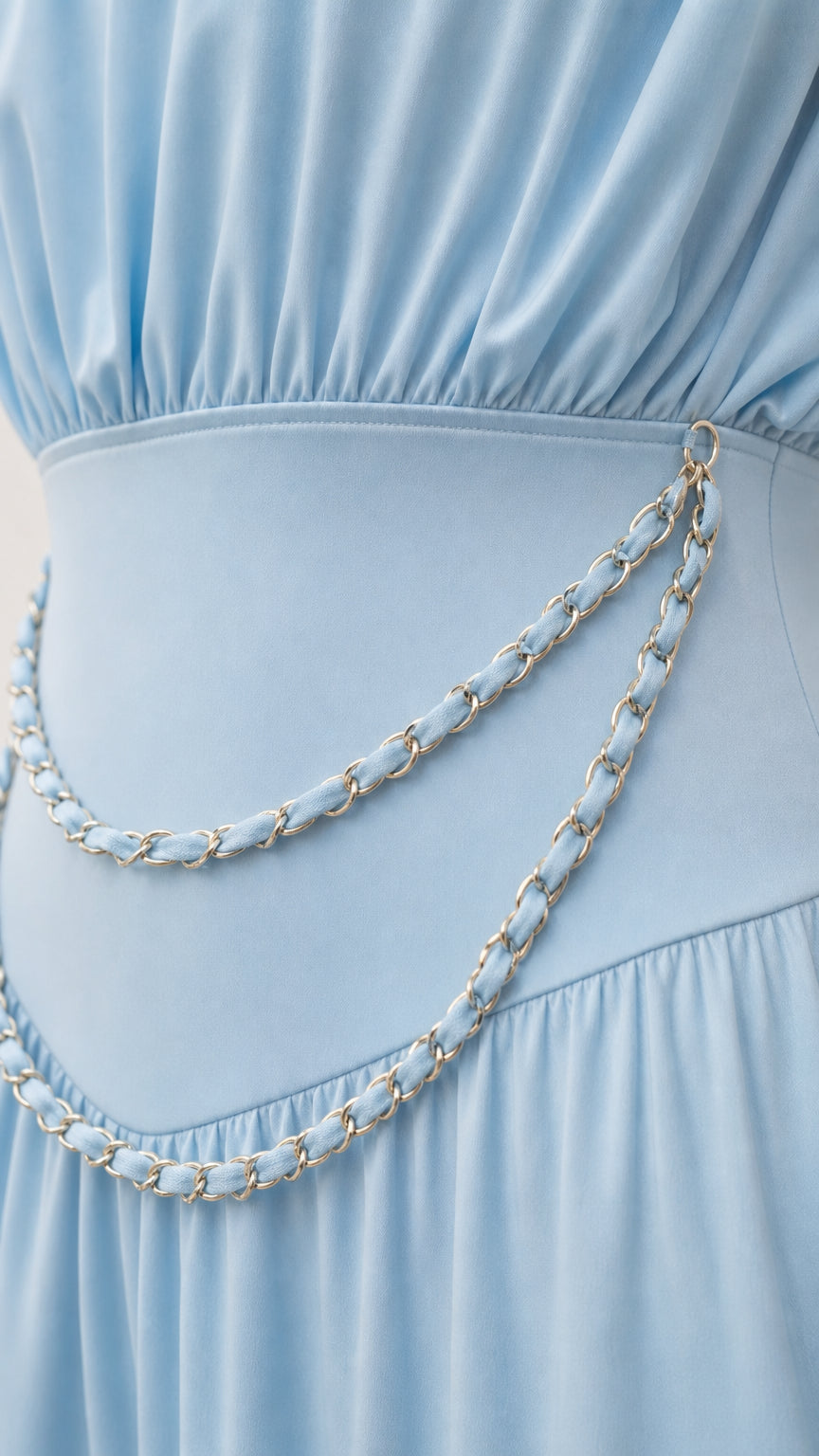 Close-up detail of draped bodice and metallic chain waist